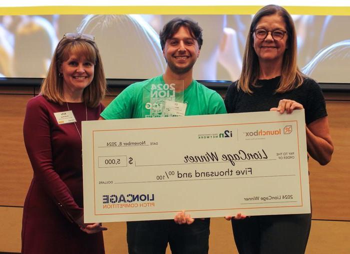 Eli Moraru, co-founder of the Community Grocer, poses with a giant check with prize money for his winning pitch.